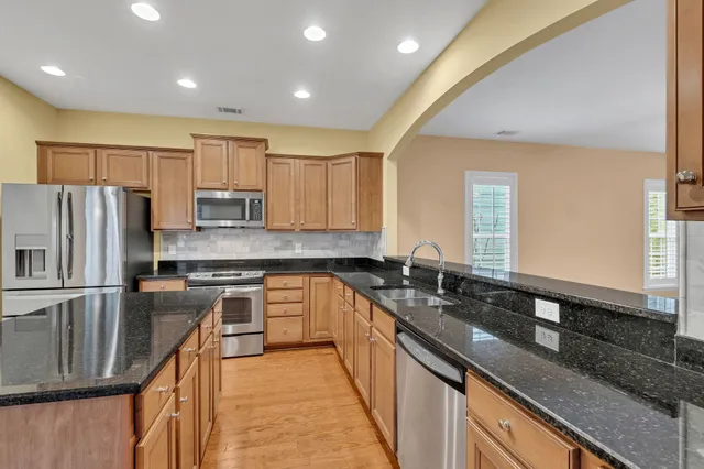 a kitchen with stainless steel appliances granite countertop a sink stove microwave and refrigerator