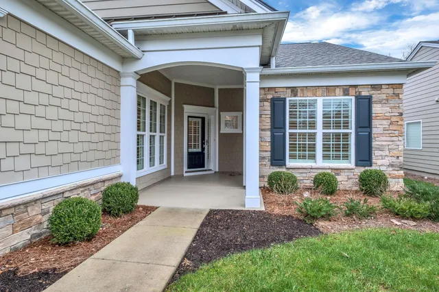 a front view of a house with garden and glass windows