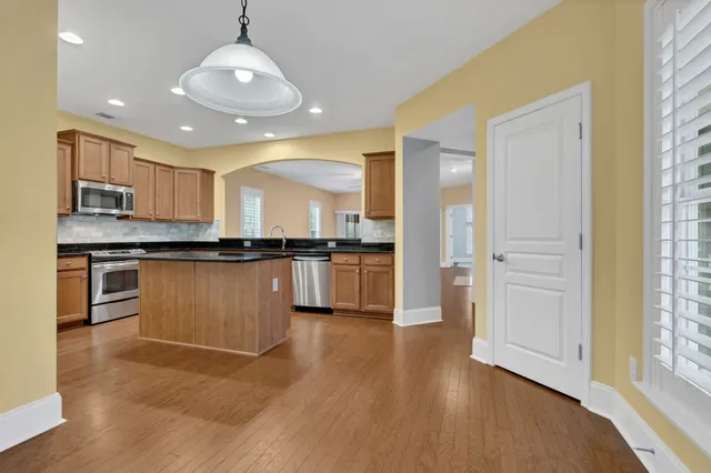 a view of kitchen with granite countertop stainless steel appliances and wooden floor