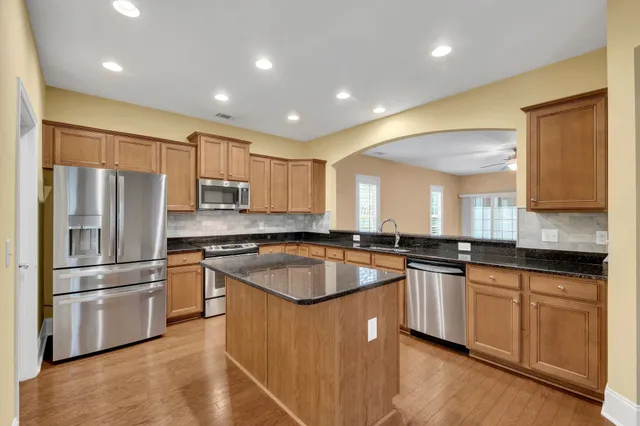 a kitchen with stainless steel appliances granite countertop a sink a stove a refrigerator a microwave oven with white cabinets