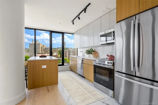 a kitchen with stainless steel appliances granite countertop a refrigerator a sink a stove and white cabinets with wooden floor