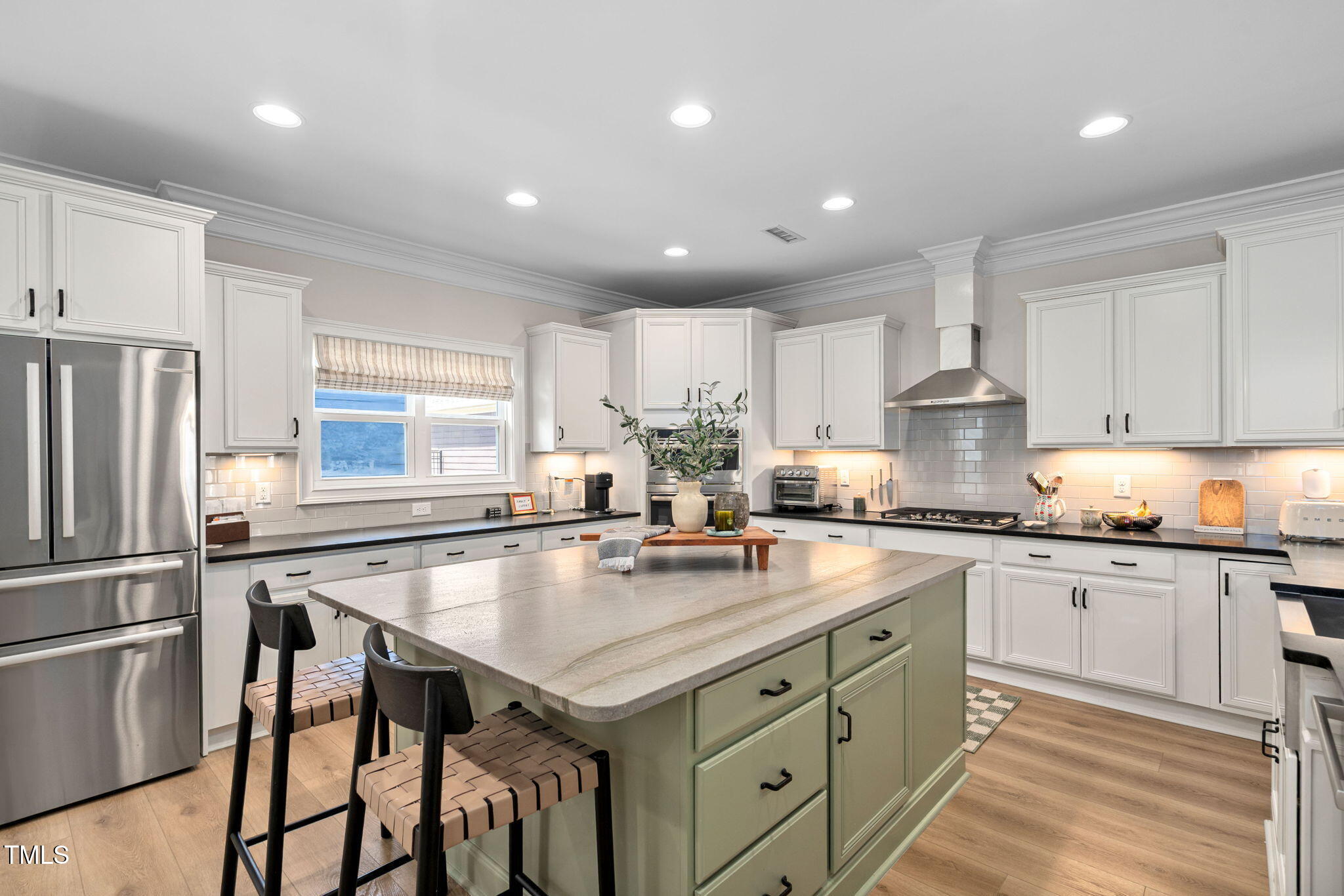 a kitchen with a stove a sink a refrigerator and white cabinets with wooden floor