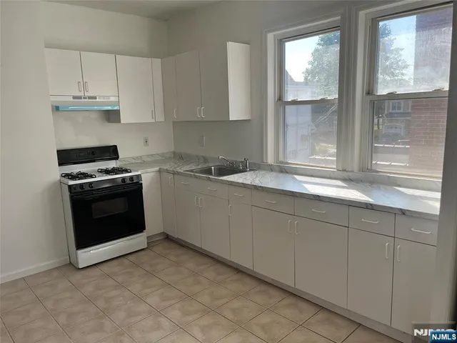 a kitchen with granite countertop white cabinets and a stove