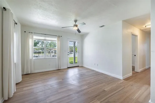 a view of an empty room with a window and wooden floor