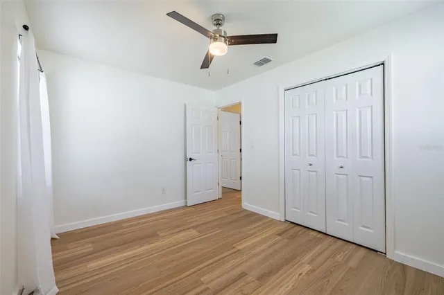 a view of empty room with wooden floor and ceiling fan