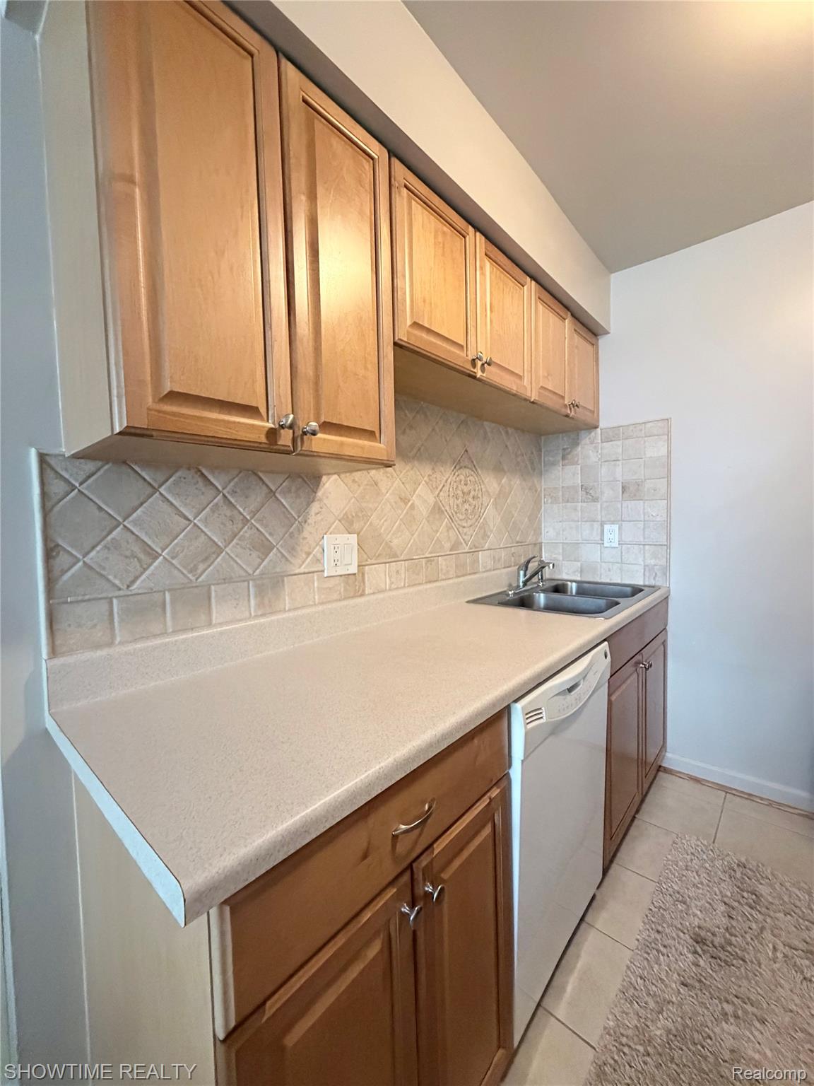 29117 Hayes Road, Unit 3 Warren, MI 48088 - Photo 9 of 14 Kitchen featuring wood-finish cabinetry, light-toned countertops, and a tiled backsplash