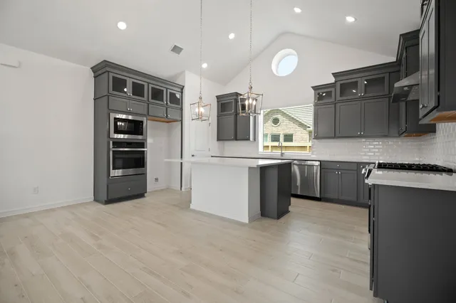 a kitchen with stainless steel appliances granite countertop a refrigerator and a stove top oven