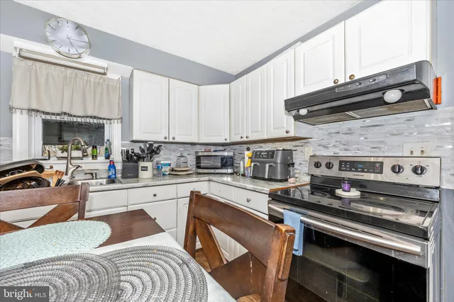 a kitchen with stainless steel appliances granite countertop a sink a stove top oven a counter space and cabinets