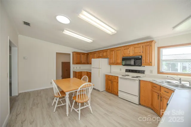 a kitchen with stainless steel appliances granite countertop a stove top oven a sink dishwasher a dining table and chairs with wooden floor