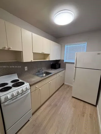 a kitchen with granite countertop white cabinets and white appliances
