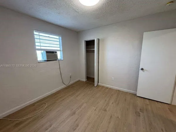 an empty room with wooden floor closet and windows