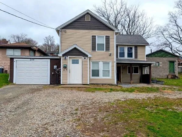 a view of a house with a yard and large tree