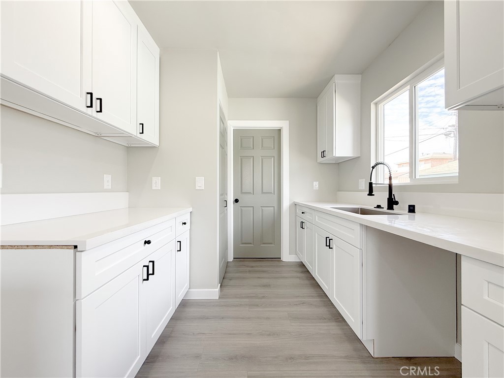 1506 West Stockwell Street Compton, CA 90222 - Photo 8 of 20 a large white kitchen with cabinets a sink a window and a refrigerator