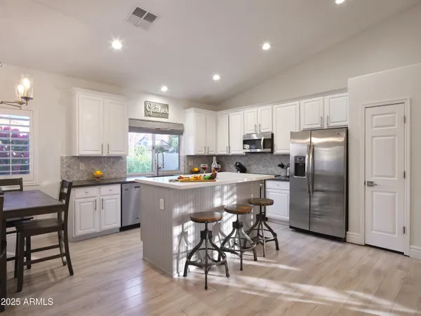 a kitchen with refrigerator a sink and chairs