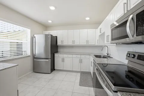 a kitchen with stainless steel appliances granite countertop a stove microwave refrigerator and sink