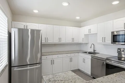 a kitchen with stainless steel appliances granite countertop a refrigerator sink and cabinets