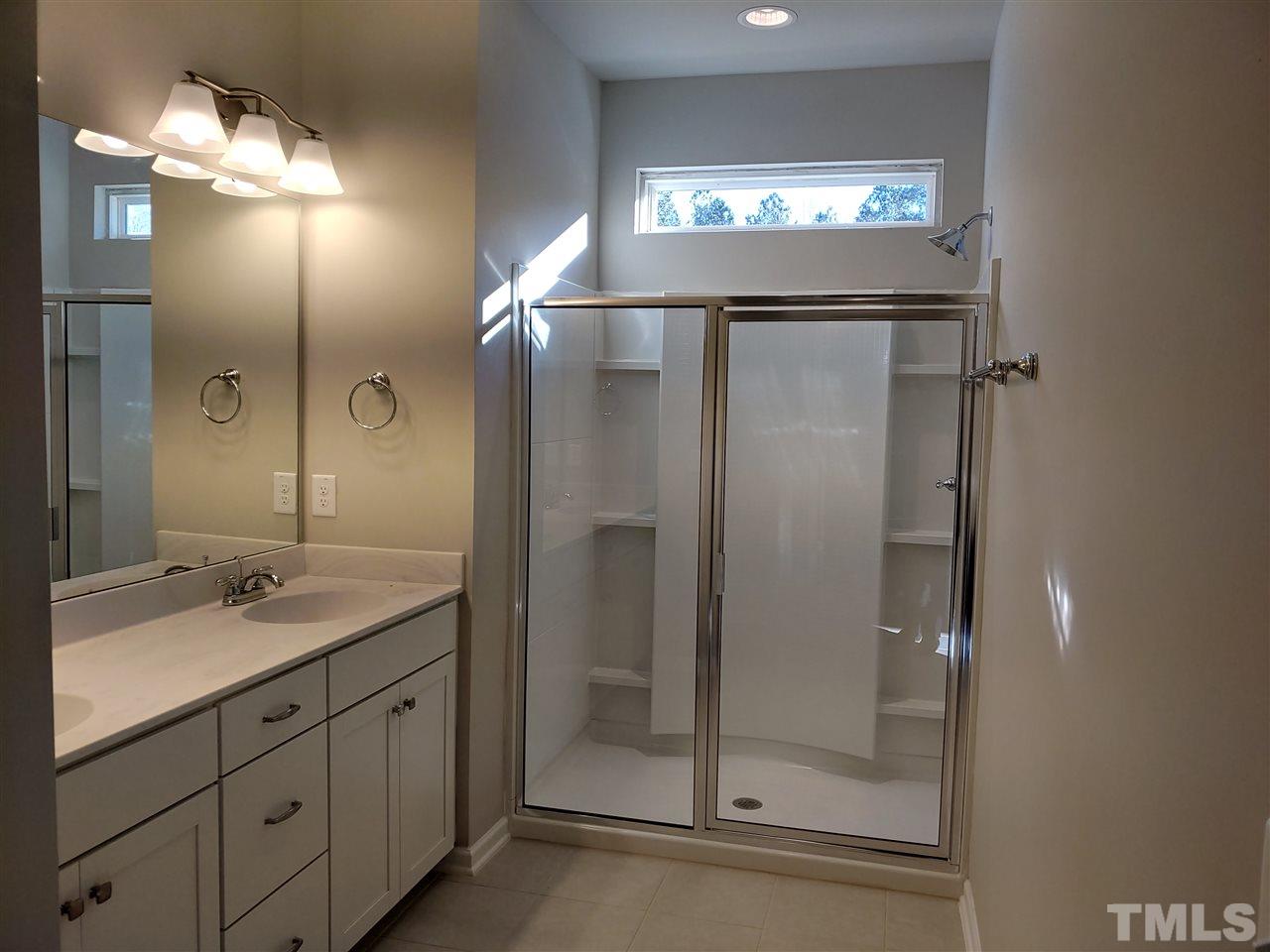 6339 Grace Lily Drive, Unit 18 Raleigh, NC 27607 - Photo 12 of 23 a bathroom with a shower a sink and a mirror