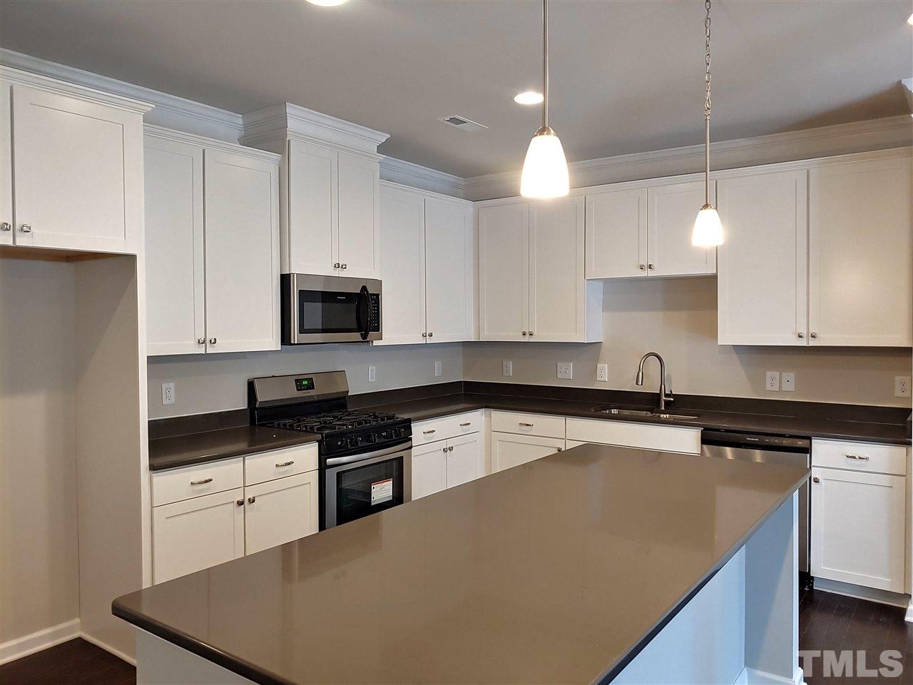 6339 Grace Lily Drive, Unit 18 Raleigh, NC 27607 - Photo 5 of 23 a kitchen with granite countertop white cabinets and black appliances