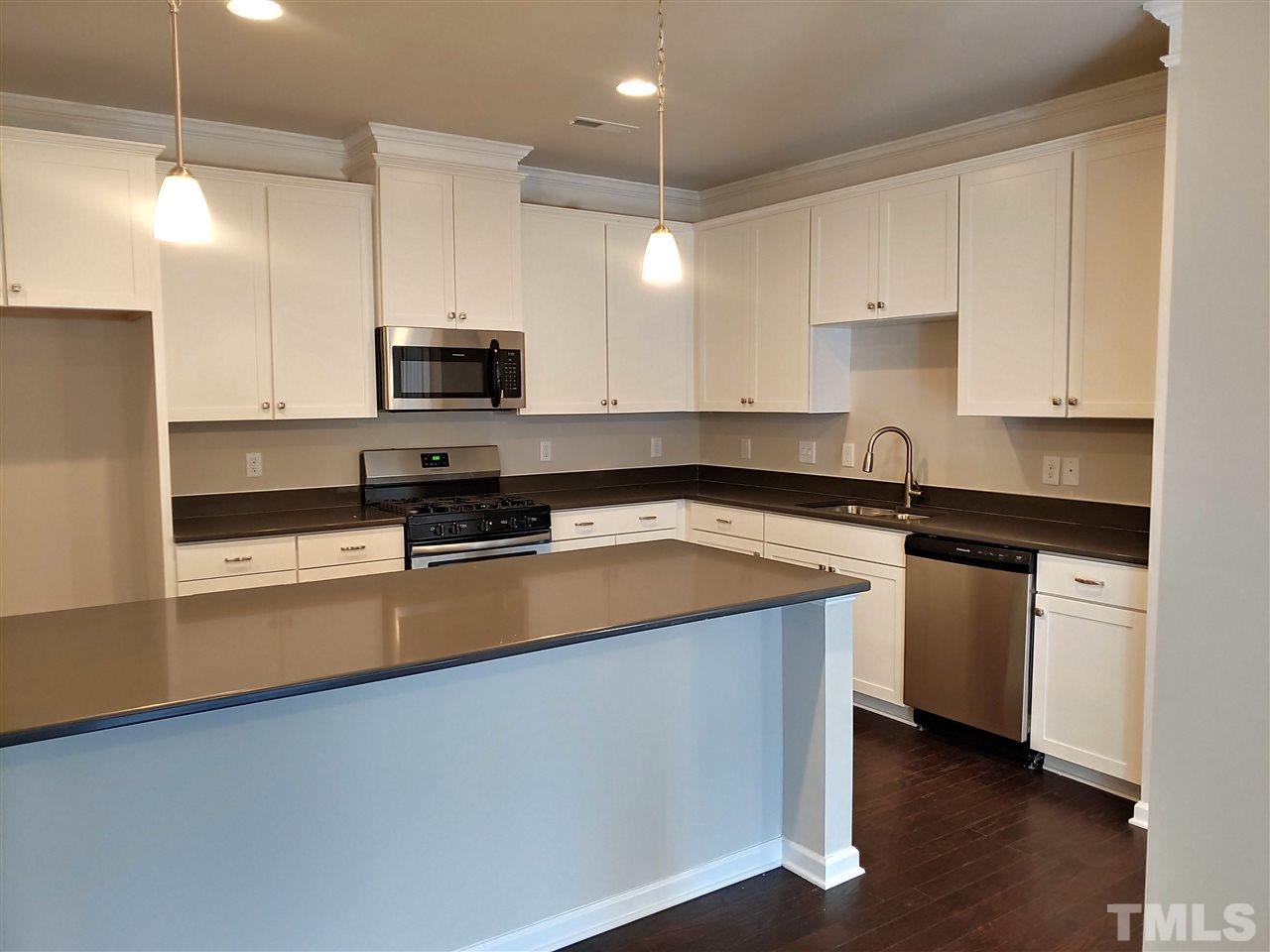 6339 Grace Lily Drive, Unit 18 Raleigh, NC 27607 - Photo 6 of 23 a kitchen with stainless steel appliances granite countertop a sink a stove and a refrigerator