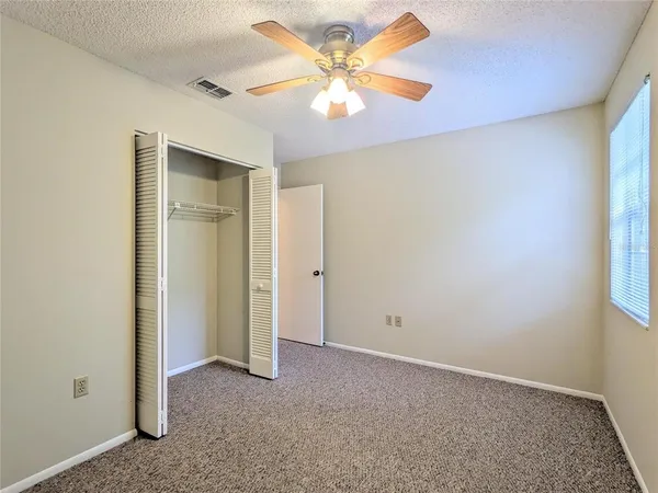 an empty room with a window and a fan