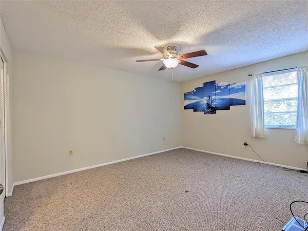 an empty room with windows and fan