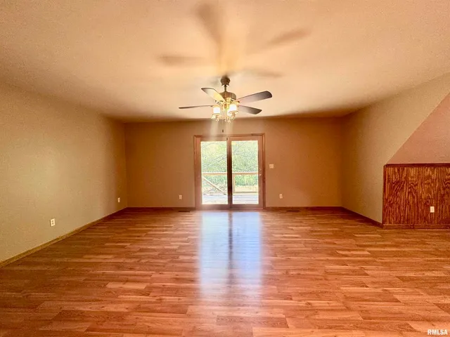a view of an empty room with window and wooden floor