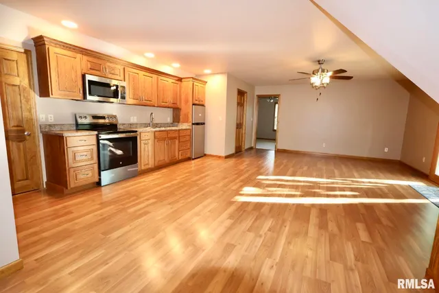 a view of a kitchen with wooden floor a sink a refrigerator and window