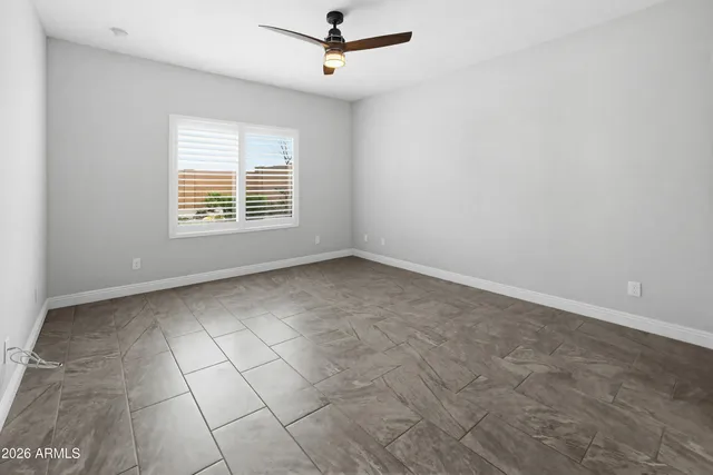an empty room with a ceiling fan and window