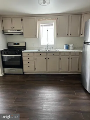 a kitchen with granite countertop a stove cabinets and a wooden floor