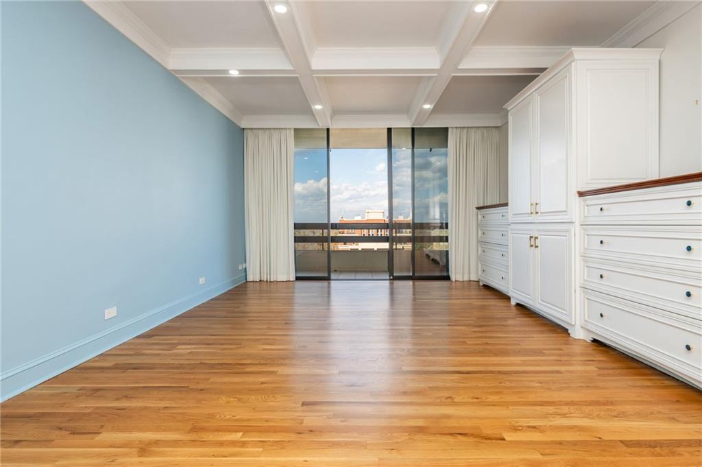 2660 Peachtree Road Northwest, Unit 22E Atlanta, GA 30305 - Photo 14 of 48 a view of an empty room with wooden floor kitchen view and a window