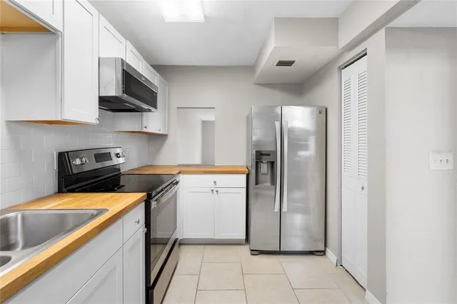 a kitchen with stainless steel appliances granite countertop a refrigerator a sink a stove top oven and cabinets