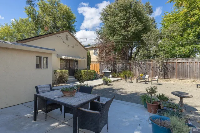 a view of a patio with table and chairs potted plants and large tree