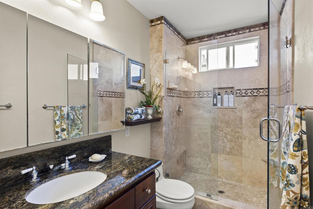 4627 Huggins Street University City, CA 92122 - Photo 26 of 54 a bathroom with a granite countertop sink a toilet a mirror and shower