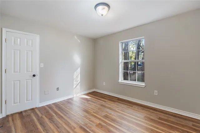 an empty room with wooden floor chandelier fan and windows
