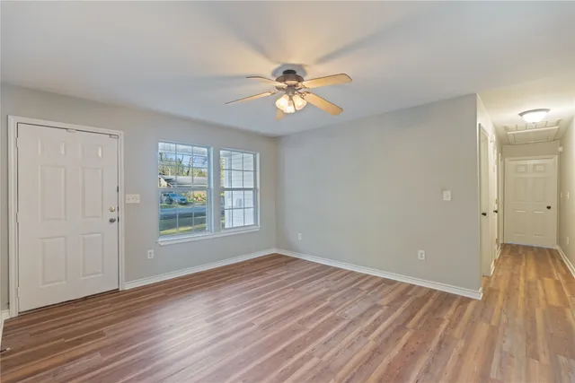 a view of empty room with wooden floor and fan