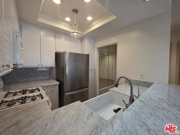 a kitchen with stainless steel appliances granite countertop a refrigerator a sink a stove and a refrigerator with wooden floor