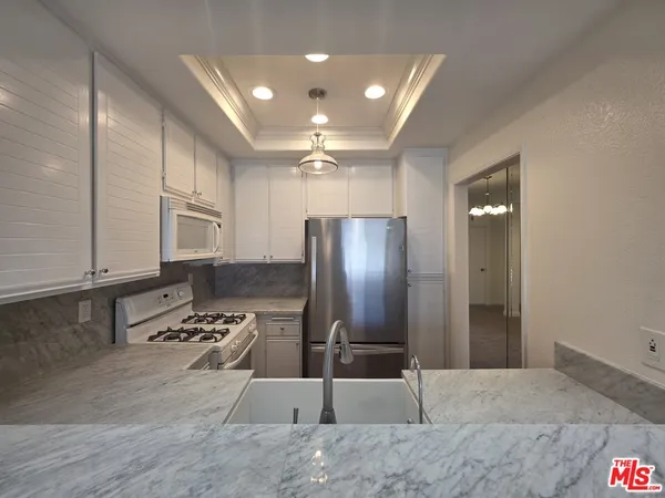 a kitchen with stainless steel appliances granite countertop a refrigerator and a stove top oven