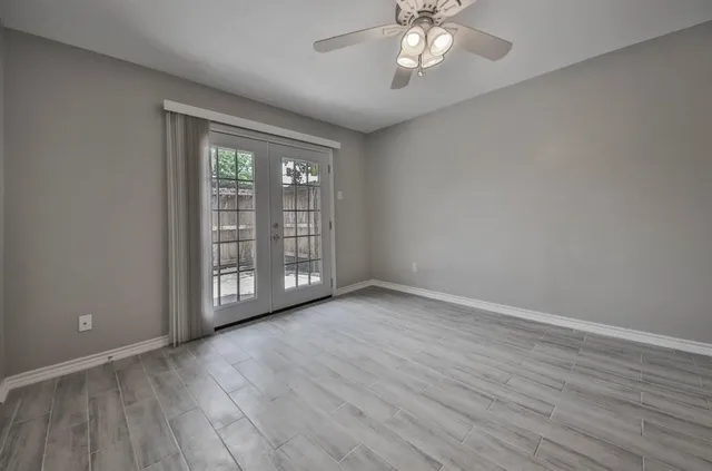 a view of an empty room with wooden floor and a window