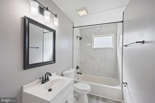 a bathroom with a bathtub shower sink mirror and toilet