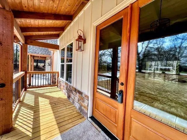 a view of an empty room with wooden floor and a kitchen