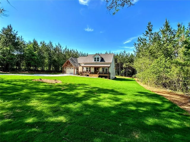 a view of a house with a big yard plants and large trees