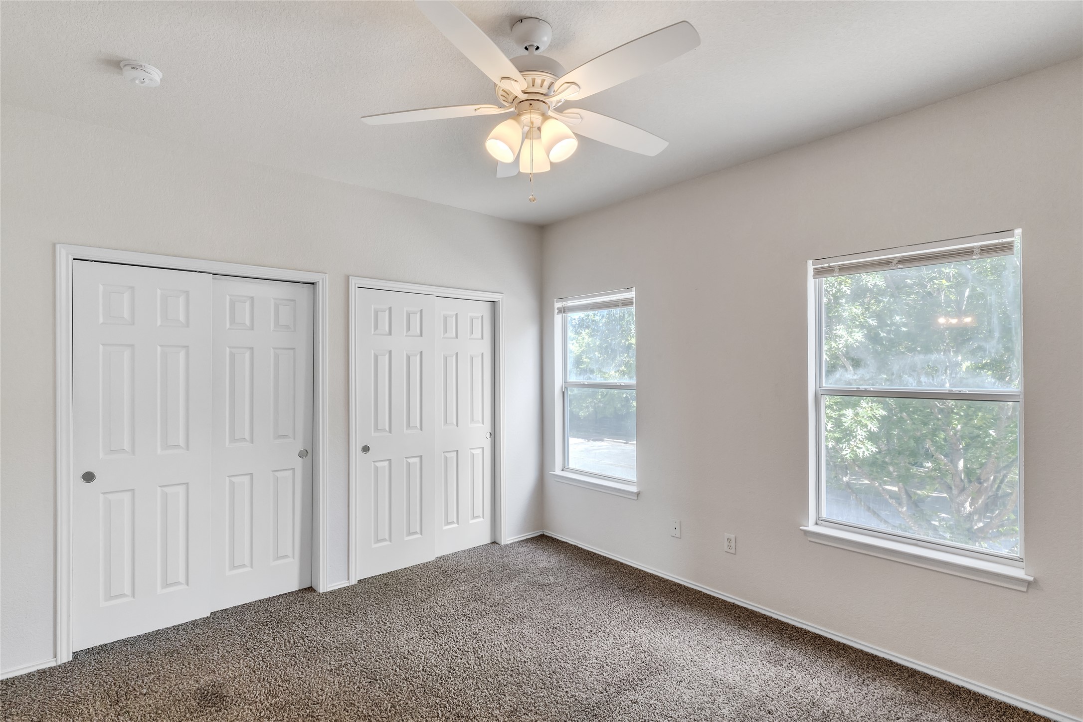 1107 East 3rd Street Georgetown, TX 78626 - Photo 36 of 36 Unfurnished bedroom with two closets, dark colored carpet, and a ceiling fan