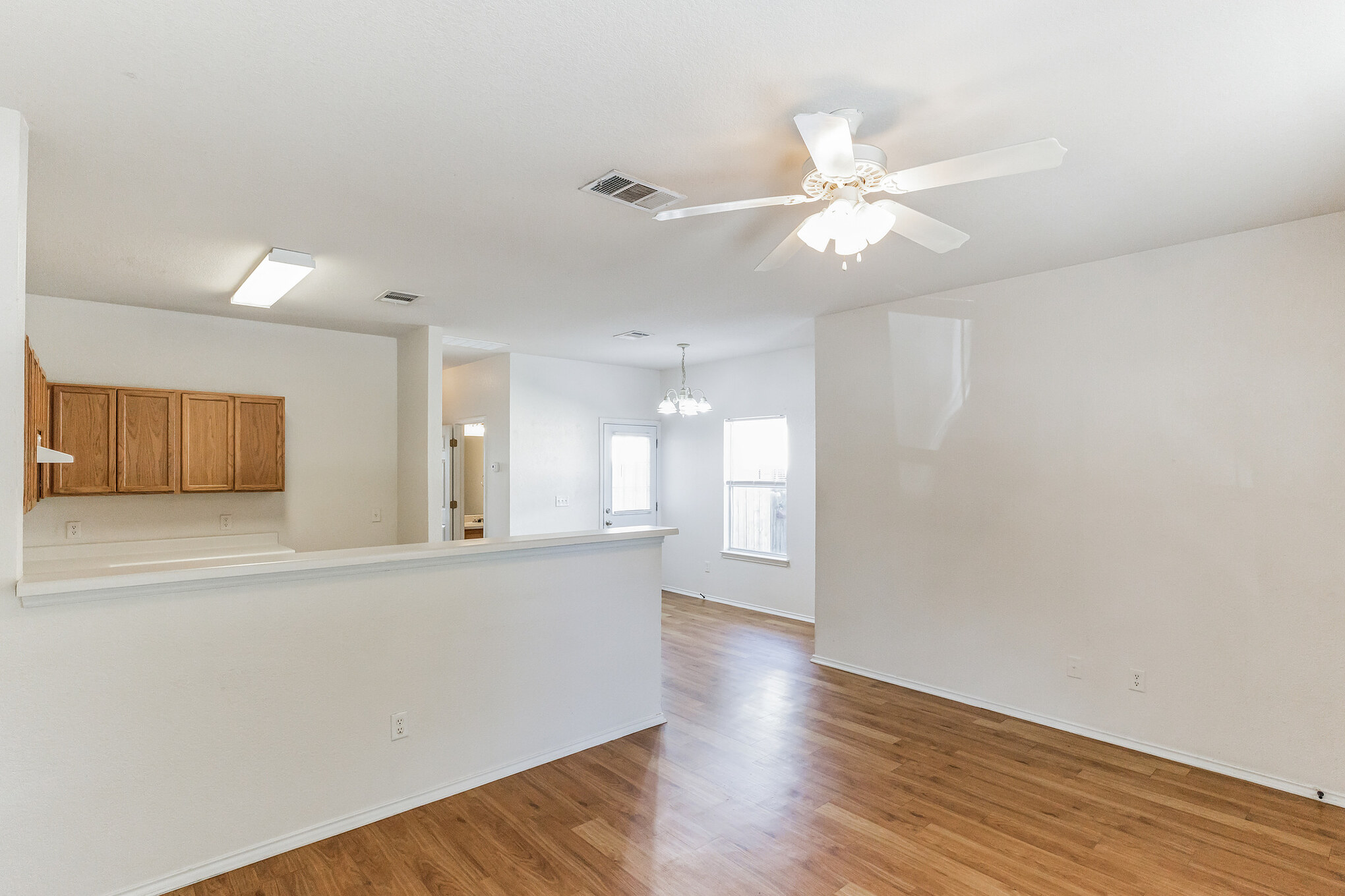 1107 East 3rd Street Georgetown, TX 78626 - Photo 5 of 36 Spare room featuring ceiling fan, light wood finished floors, and suspended lighting