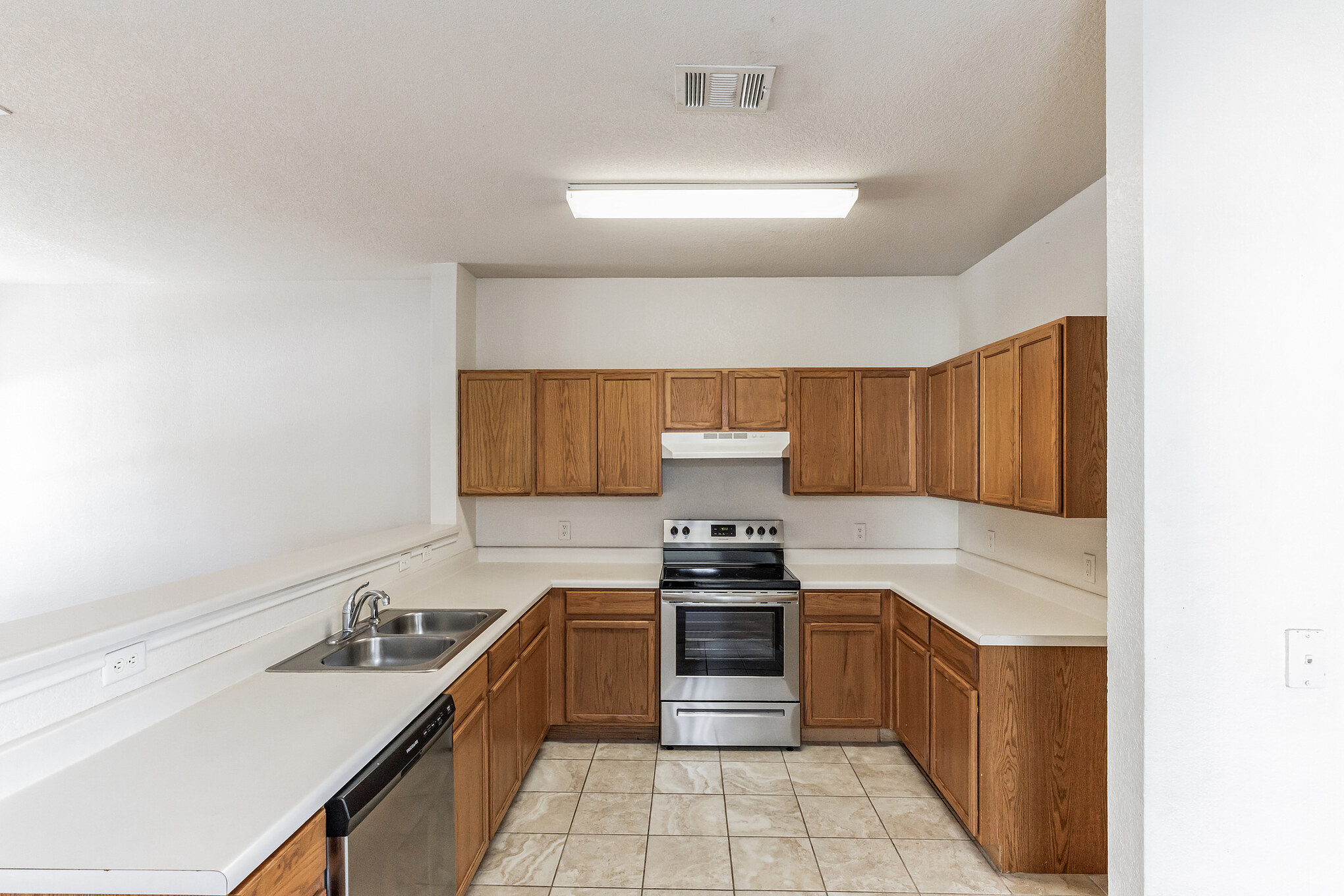 1107 East 3rd Street Georgetown, TX 78626 - Photo 7 of 36 Kitchen featuring stainless steel appliances, light countertops, wood finish cabinetry, light tile patterned floors, and a peninsula