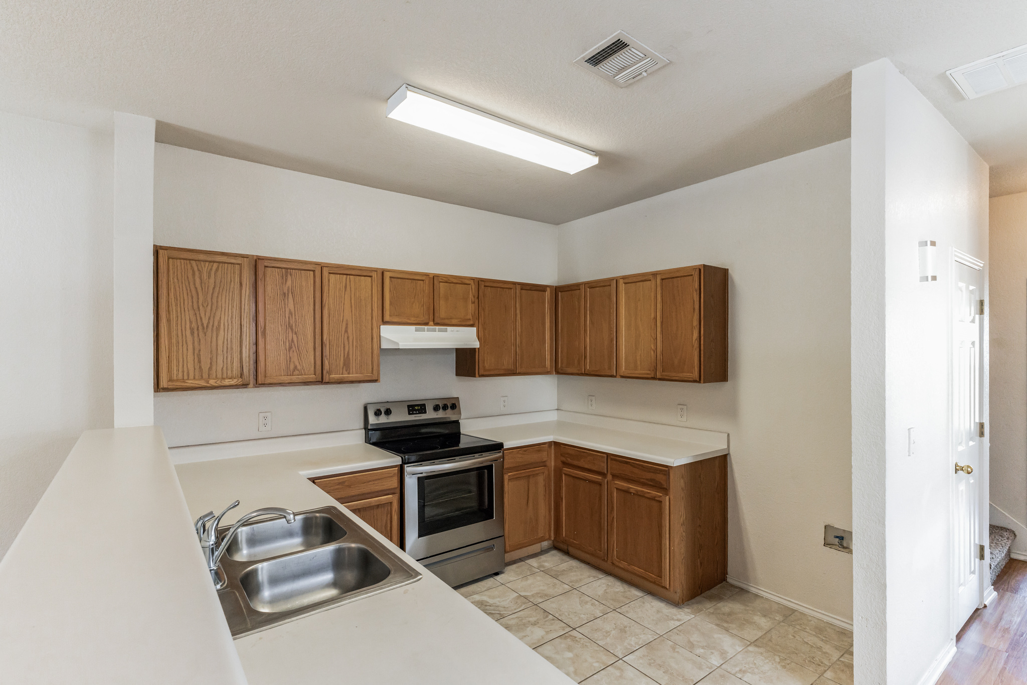 1107 East 3rd Street Georgetown, TX 78626 - Photo 8 of 36 Kitchen featuring electric stove, light countertops, wood finish cabinetry, light tile patterned floors, and a peninsula