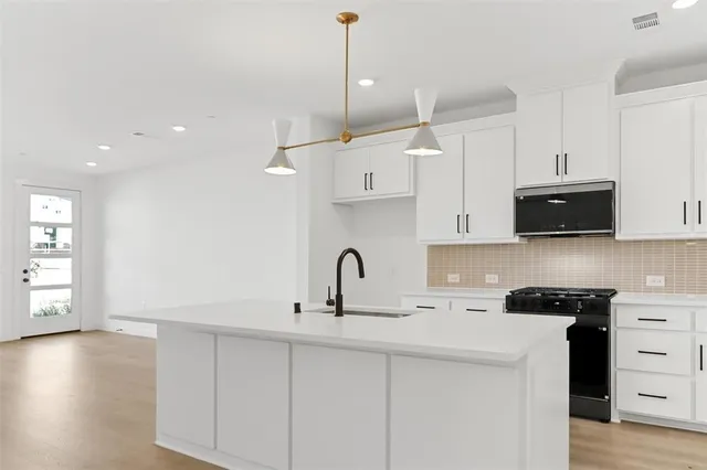 a kitchen with stainless steel appliances a sink a stove a microwave and wooden floor