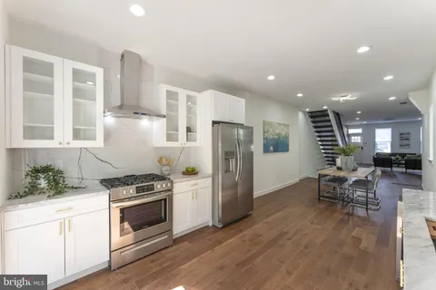 a kitchen with stainless steel appliances a refrigerator a stove a sink dishwasher and white cabinets with wooden floor