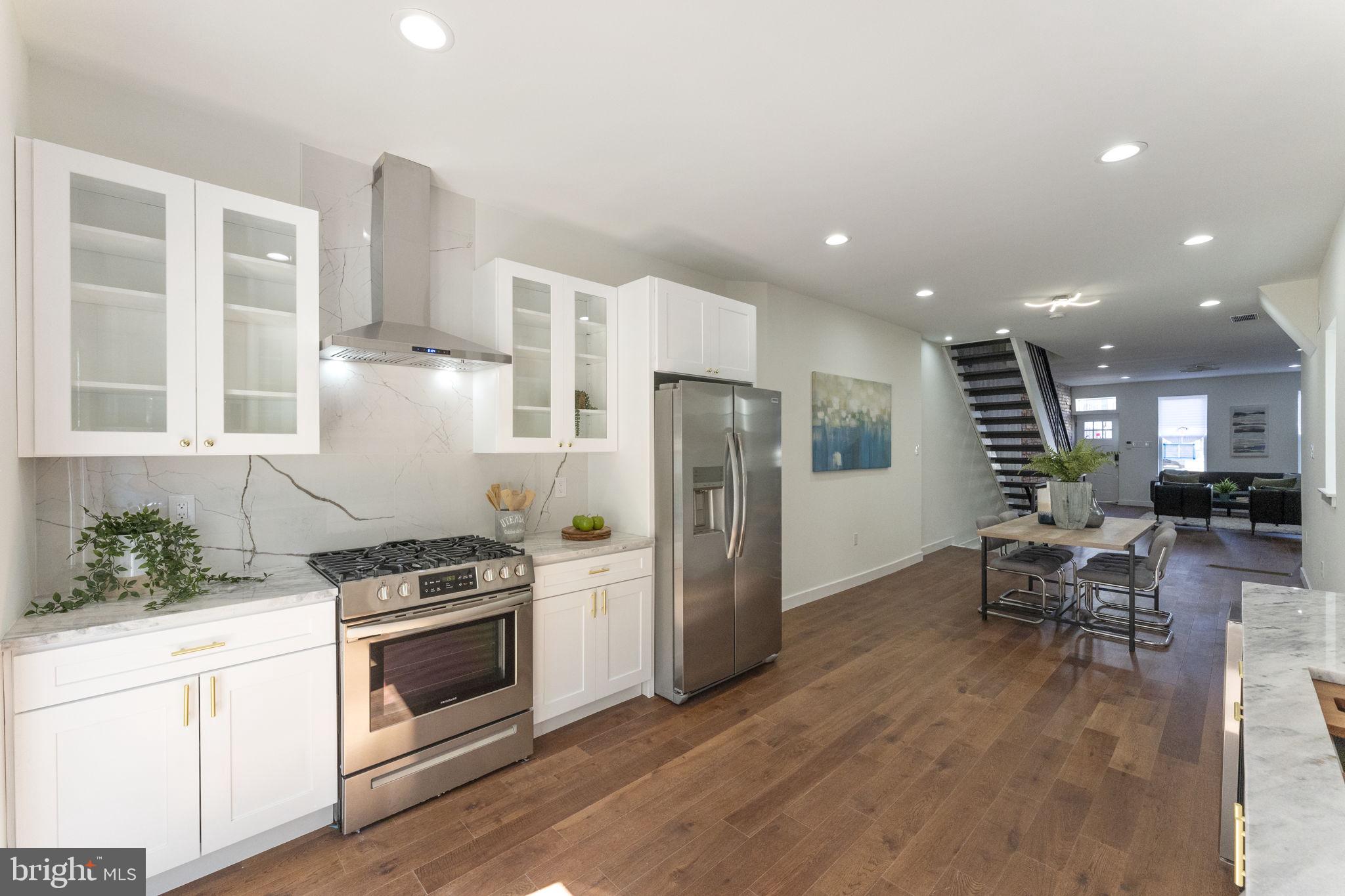 2030 Tasker Street Philadelphia, PA 19145 - Photo 13 of 29 a kitchen with stainless steel appliances a refrigerator a stove a sink dishwasher and white cabinets with wooden floor
