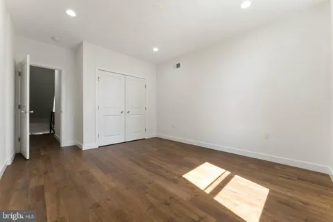 an empty room with wooden floor and natural light
