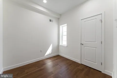an empty room with wooden floor and window